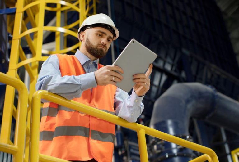 Colaborador com EPI e um tablet na mão