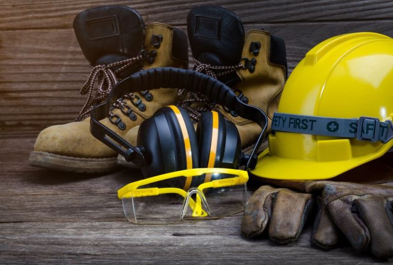 EPIs na imagem, com botas, abafador de som, capacete e óculos.